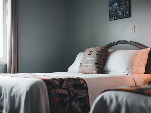 Quarto com duas camas arrumadas e luz suave de fim de tarde